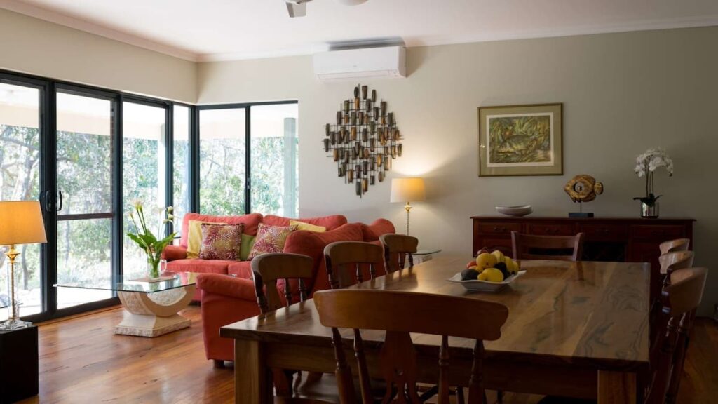 Vaila's living area with large wooden dining table with an L-shaped red couch