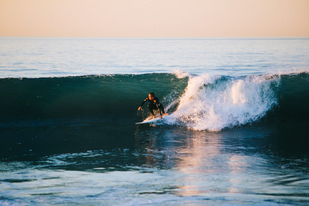 A surfer skillfully riding a perfect wave at sunset, showcasing the thrilling experience of surfing in Western Australia, known for its world-class waves and stunning coastal scenery