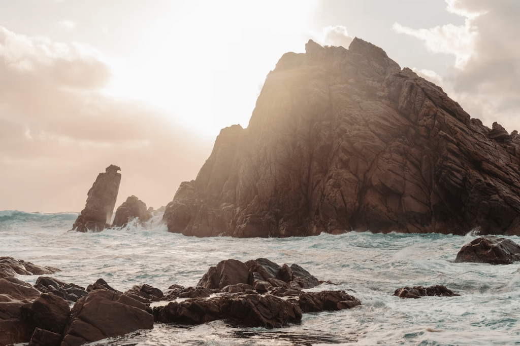 Panoramic view of the rugged coastline along the Sugarloaf Rock Trail in Dunsborough, WA, featuring a clear blue sky, azure waters, and dramatic rock formations
