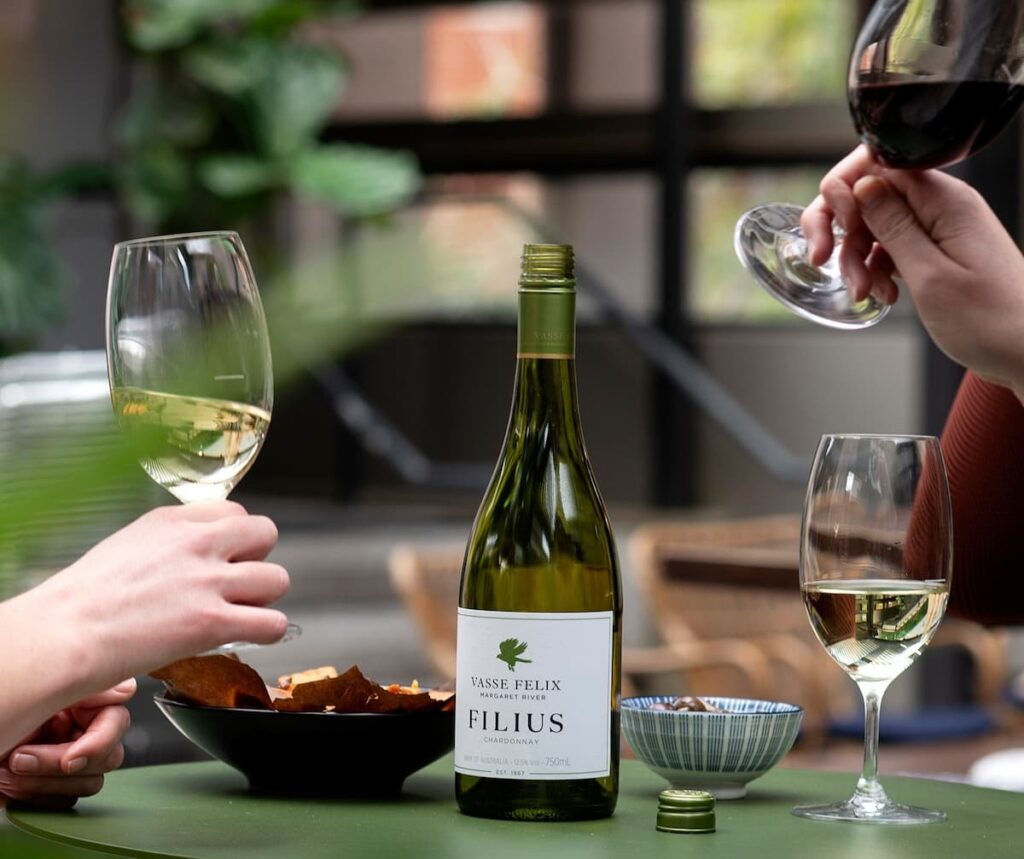 Three wine glasses and a bottle of white wine with two bowls