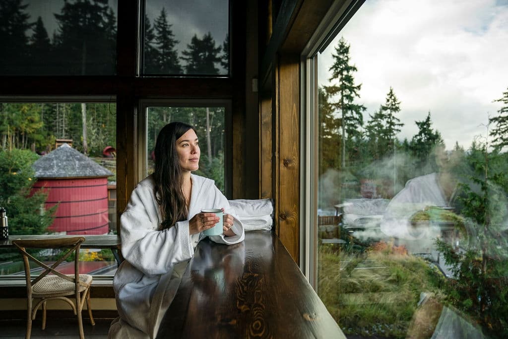 Woman drinking from a mug wearing a white robe while at the spa in Whistler in Autumn