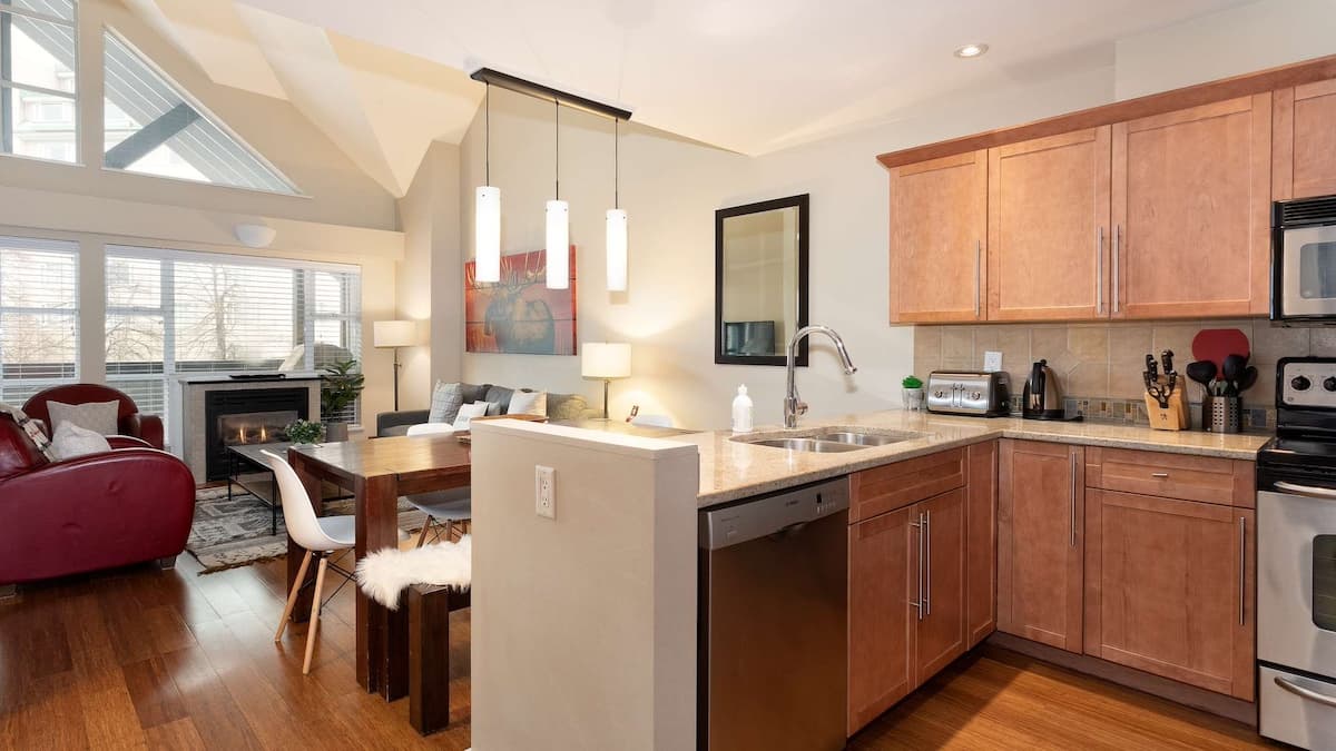 Light brown wood kitchen with dishwasher integrated into spacious dining and living space