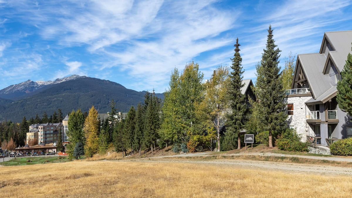 Brown grass run next to the ski-in ski-out aspens location with mountain views and blue skies in background 