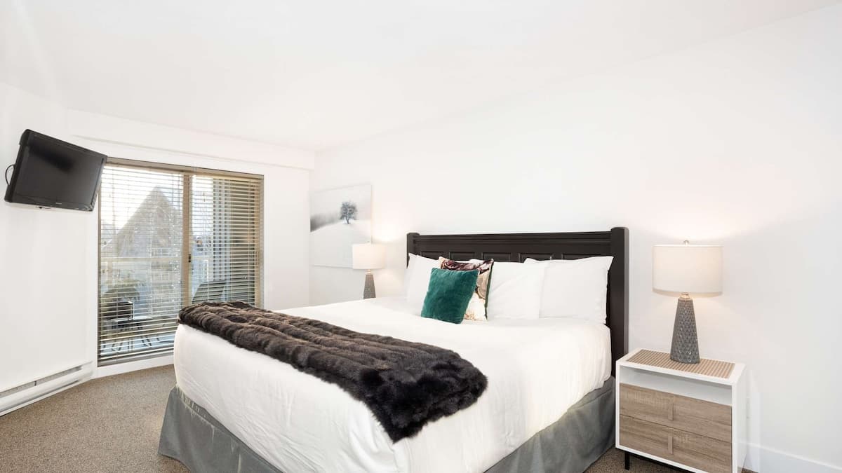 Large white bedroom with big bed and sliding doors out to private balcony