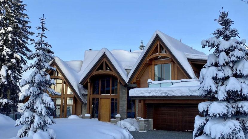 Luxury home with snow covered trees next to the house