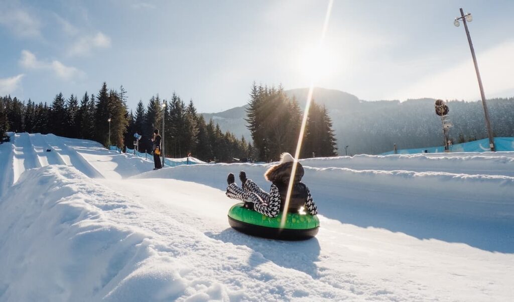 Tubing at Whistler tube park in winter surrounded by snow on a sunny day