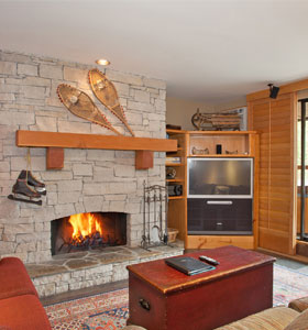 a pair of snow shoes and a mantle hang from a stone fireplace in a whistler, ca condo