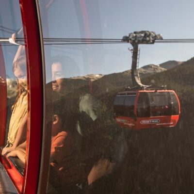 Family soaring in the Peak 2 Peak Gondola over Whistler’s epic alpine forest, with another cabin gliding in the distance