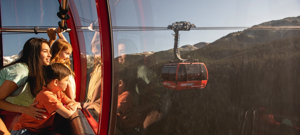 Family soaring in the Peak 2 Peak Gondola over Whistler’s epic alpine forest, with another cabin gliding in the distance